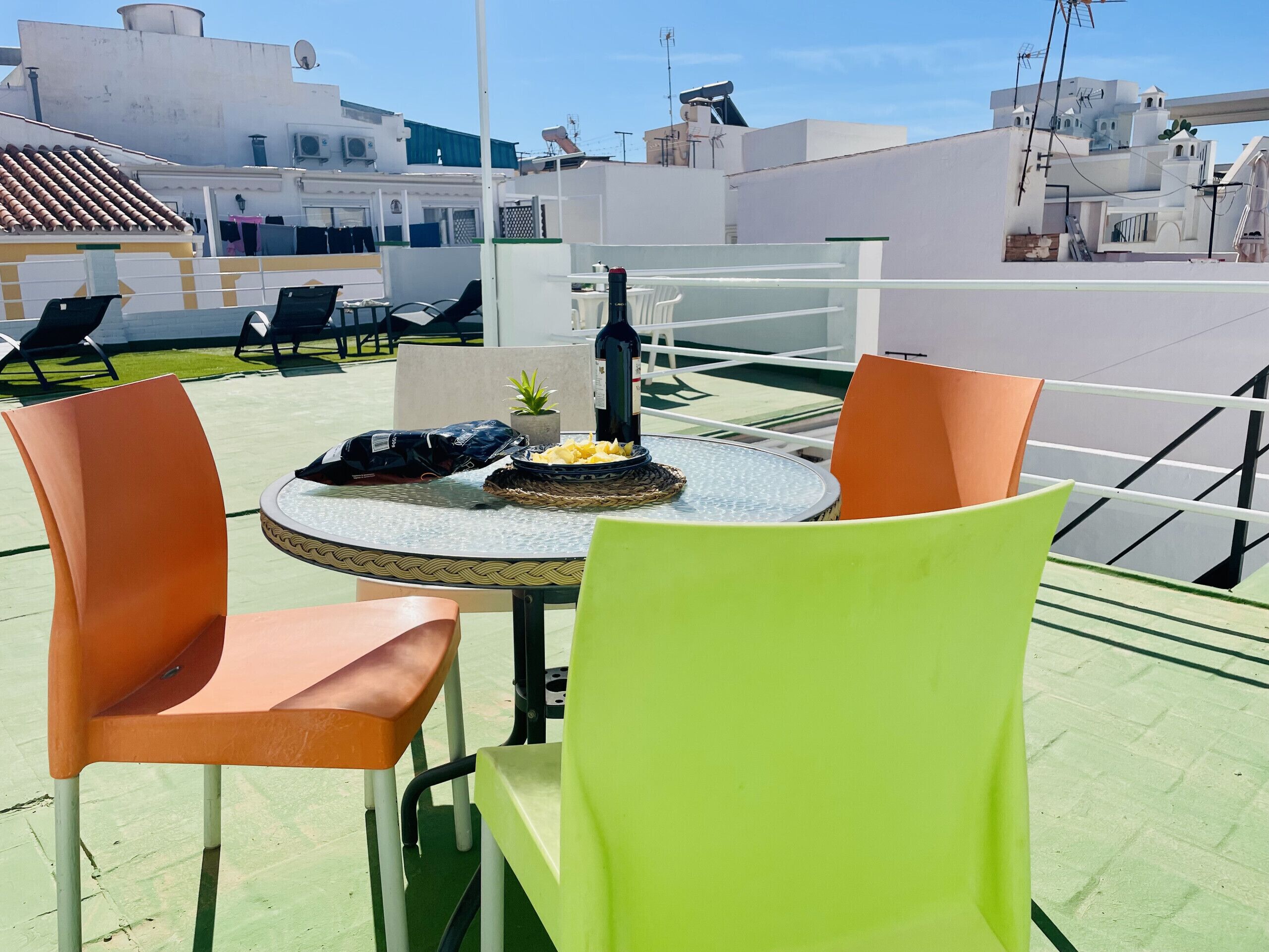 Eine Dachterrasse mit rundem Tisch, zwei Stühlen, einer Flasche und einer Obstschale.