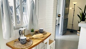 Een eetruimte met een houten tafel, witte stoelen, een raam met gordijnen en uitzicht op een stadsgezicht.
