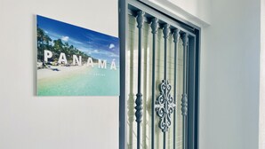 Een deur met een decoratief metalen rooster en een lijst met een afbeelding van een strand, met de tekst 'PANAMÁ' en 'ARTAMENTO CARIBE' op de muur.