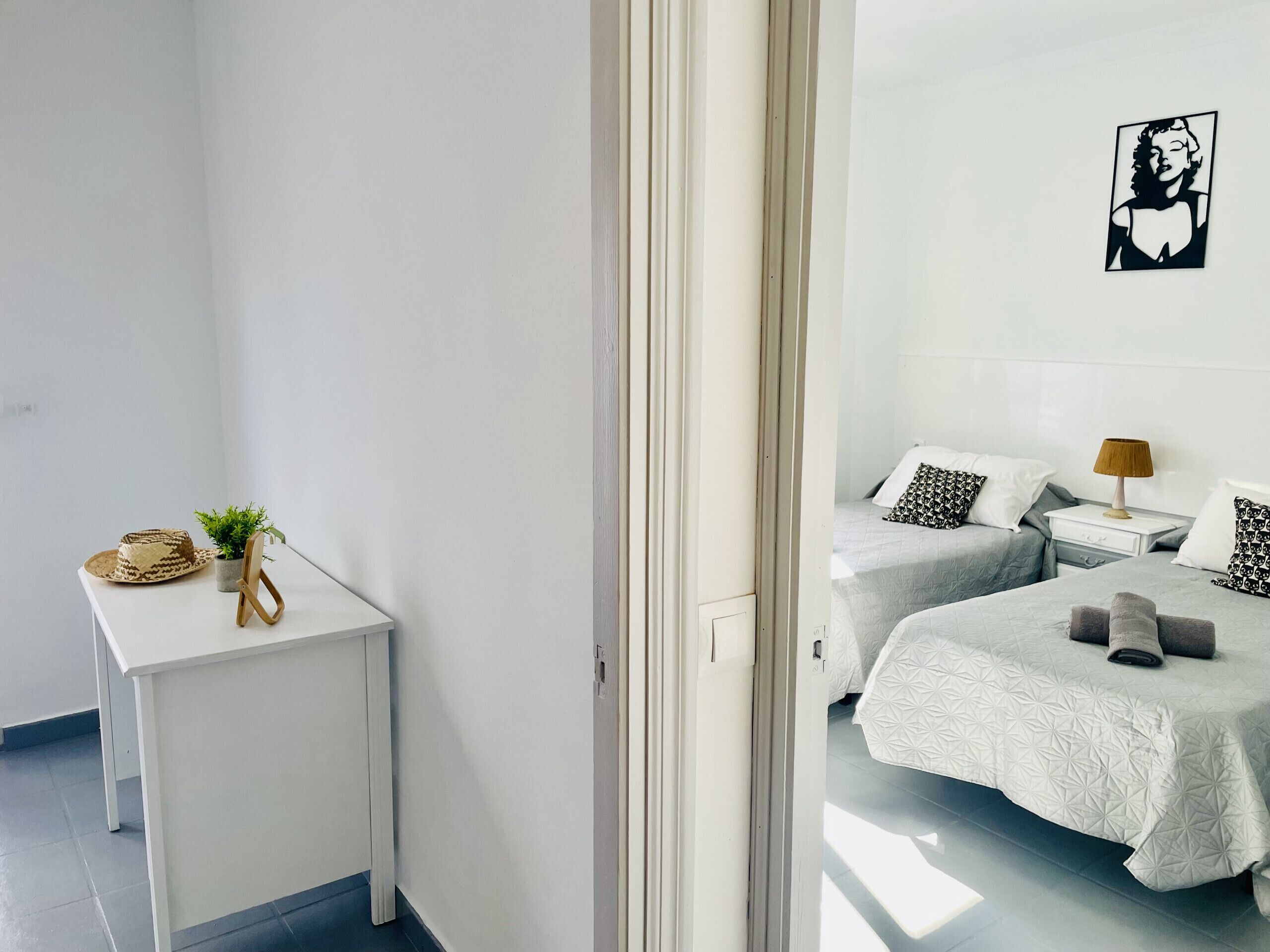 A hotel room with a bed, bedside table, lamp, and a wall-mounted picture.