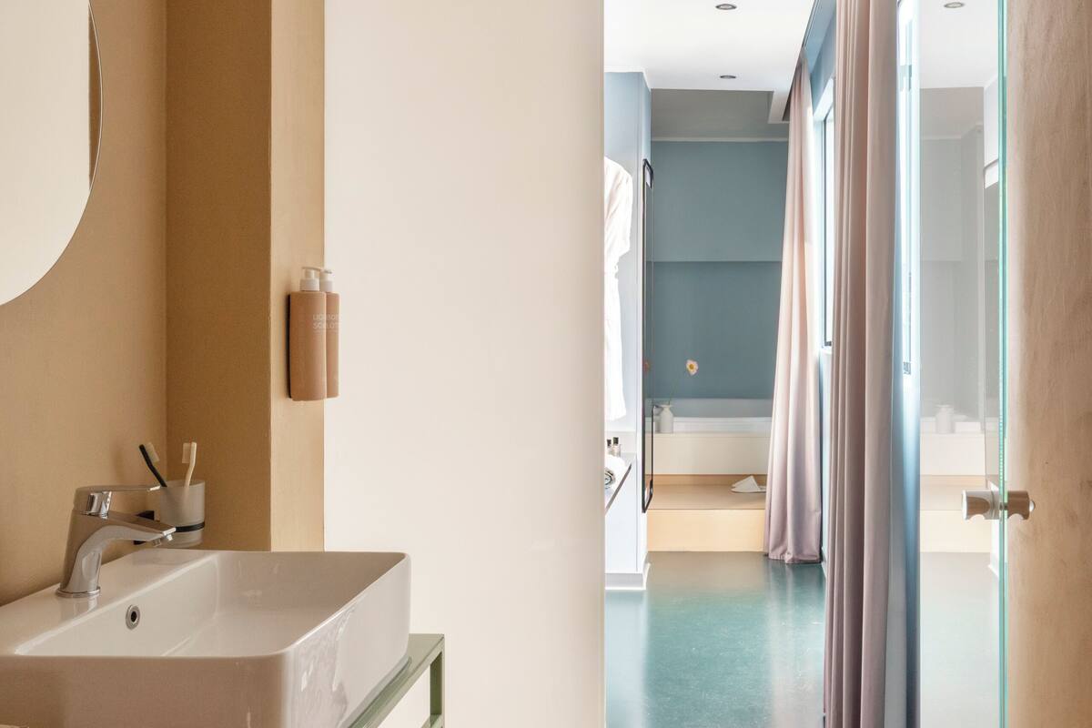 A modern bathroom with a large mirror, a sink, and a shower area.