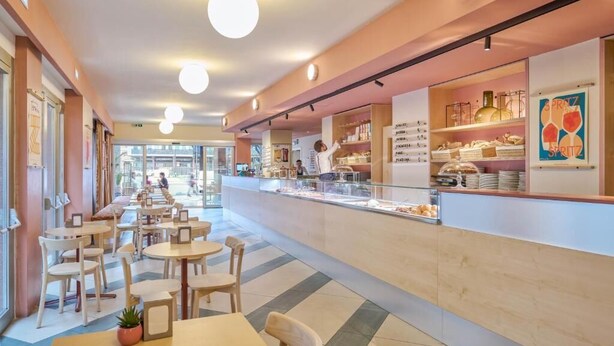 A cafe with a counter, tables, chairs, and a glass display case. - Moderno Hotel Roma (Rome)