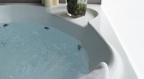A bathtub filled with water, a white towel, and a glass with flowers. - Moderno Hotel Roma (Rome)