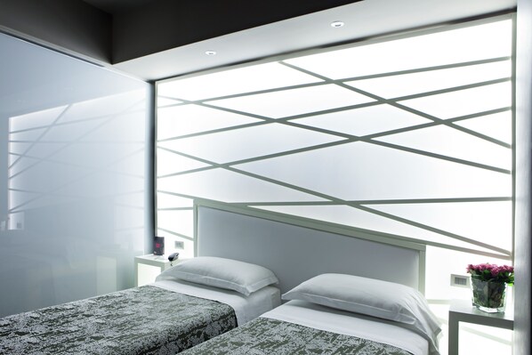 A modern bedroom with two beds, a skylight, and a bedside table with a vase. - Moderno Hotel Roma (Rome)