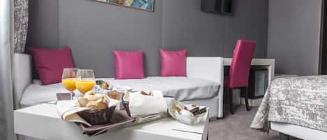 Habitación de hotel con una cama, una mesa con desayuno, un televisor y un cuadro en la pared.