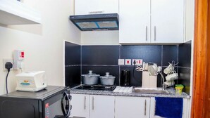 Eine kleine Küche mit Mikrowelle, Herd und Töpfen auf der Arbeitsfläche.
