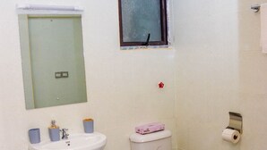 Ein Badezimmer mit Waschbecken, Toilette und einem kleinen Fenster.