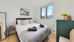 A bedroom with a bed, bedside table, window, and artwork. - Peaceful 1 bed apt in the Heart of Fitzrovia (London)