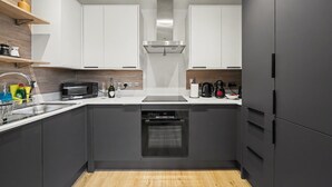 A modern kitchen with a dishwasher, oven, microwave, and a stainless steel range hood. - Peaceful 1 bed apt in the Heart of Fitzrovia (London)