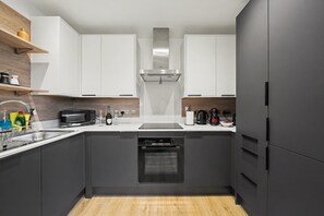 A modern kitchen with white cabinets, a built-in oven, and a stainless steel range hood. - Peaceful 1 bed apt in the Heart of Fitzrovia (London)