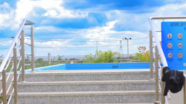 A staircase leading to a blue-tiled pool area with a signboard in the background. - Luxury Apartments with Amazing Nairobi Park Views (Nairobi)