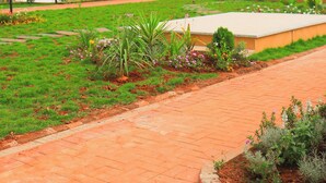 A modern building with a flat roof and a balcony, surrounded by a landscaped garden with various plants and a paved walkway. - Luxury Apartments with Amazing Nairobi Park Views (Nairobi)