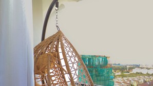 A hanging chair on a balcony with artificial grass and a view of a cityscape. - Luxury Apartments with Amazing Nairobi Park Views (Nairobi)