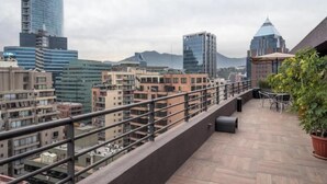 Eine Dachterrasse mit Blick auf Stadtgebäude und Berge.