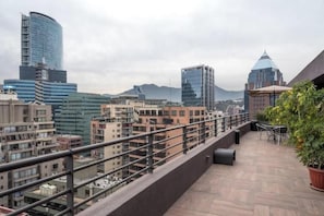Eine Dachterrasse mit Blick auf Stadtgebäude und Berge.