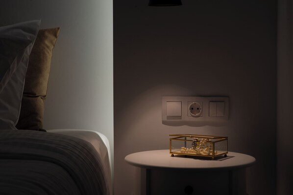 Une chambre à coucher avec un lit, une table de chevet avec une lampe et un interrupteur fixé au mur.