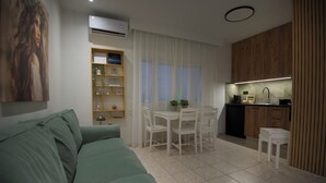 A living room with a green sofa, a dining table with chairs, a kitchen with wooden cabinets, and a white air conditioning unit. - Casa Nefeli (Heraklion)