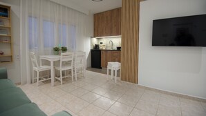A modern living room with a dining area, a kitchen, and a flat-screen TV mounted on the wall. - Casa Nefeli (Heraklion)