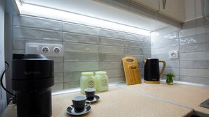 A kitchen with a coffee maker, two coffee dispensers, a knife block, and a small plant on the counter. - Casa Nefeli (Heraklion)