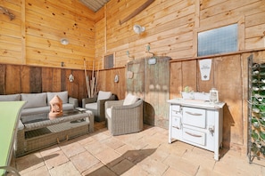 A wooden interior with wicker furniture, a vintage stove, and a wine rack.