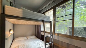 A bunk bed with a ladder, a bedside lamp, and a window with a view of greenery. - “Merge Hostel Chinatown — Hidden Chinese Stay in the heart of Yaowarat”​ (Krung Thep Maha Nakhon)