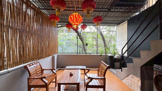 A room with a bamboo wall, a wooden table with benches, and red lanterns. - “Merge Hostel Chinatown — Hidden Chinese Stay in the heart of Yaowarat”​ (Krung Thep Maha Nakhon)