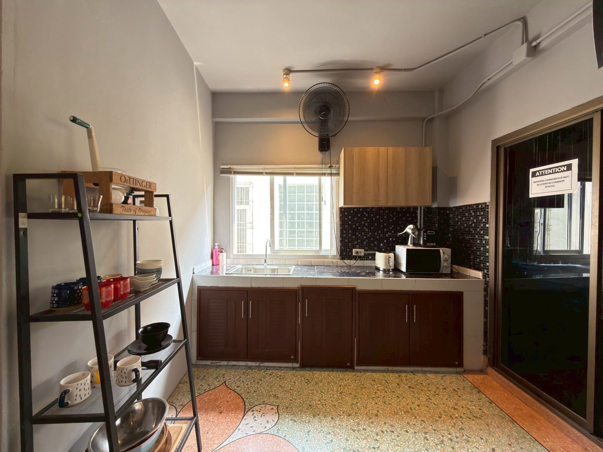 Una cocina con una isla central, un ventilador, una ventana y un letrero en la puerta.