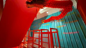 A room with a red dragon decoration, a blue corrugated wall, and a red metal chair. - “Merge Hostel Chinatown — Hidden Chinese Stay in the heart of Yaowarat”​ (Krung Thep Maha Nakhon)