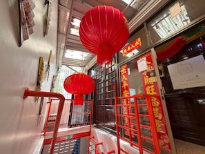 A corridor with red lanterns, a metal gate, and a sign with Chinese characters.