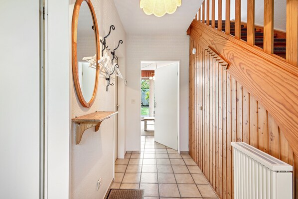 Ein Flur mit einer Holztreppe, einem weißen Heizkörper und einem Spiegel an der Wand.