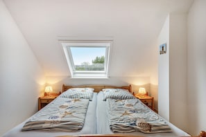 Ein Schlafzimmer mit zwei Betten, einem Oberlicht und Nachttischlampen.