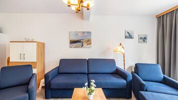 Una sala de estar moderna con un conjunto de sofá, una mesa de centro con flores, un aparador y una lámpara.