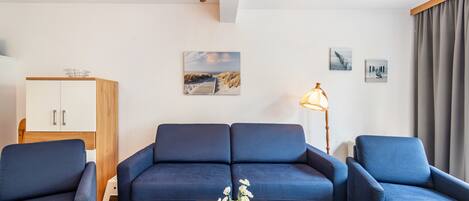 A modern living room with a sofa set, a coffee table with flowers, a cabinet, and a lamp.
