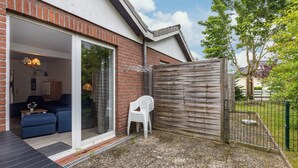 A modern house with a glass door leading to a living area, a wooden fence, and a gravel yard. - Holiday Home for 6 People (65 m²) in Dahme (Dahme)