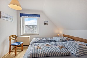 Un dormitorio con cama, una silla, un ventanal y una lámpara en el techo.
