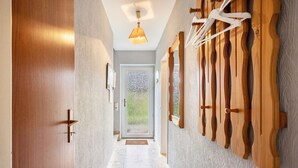 Un pasillo con puertas de madera, una lámpara colgante y un adorno de pared de madera.