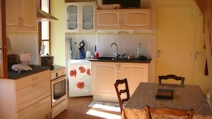Une cuisine avec des meubles blancs, une cuisinière, un évier et une table à manger avec des chaises.