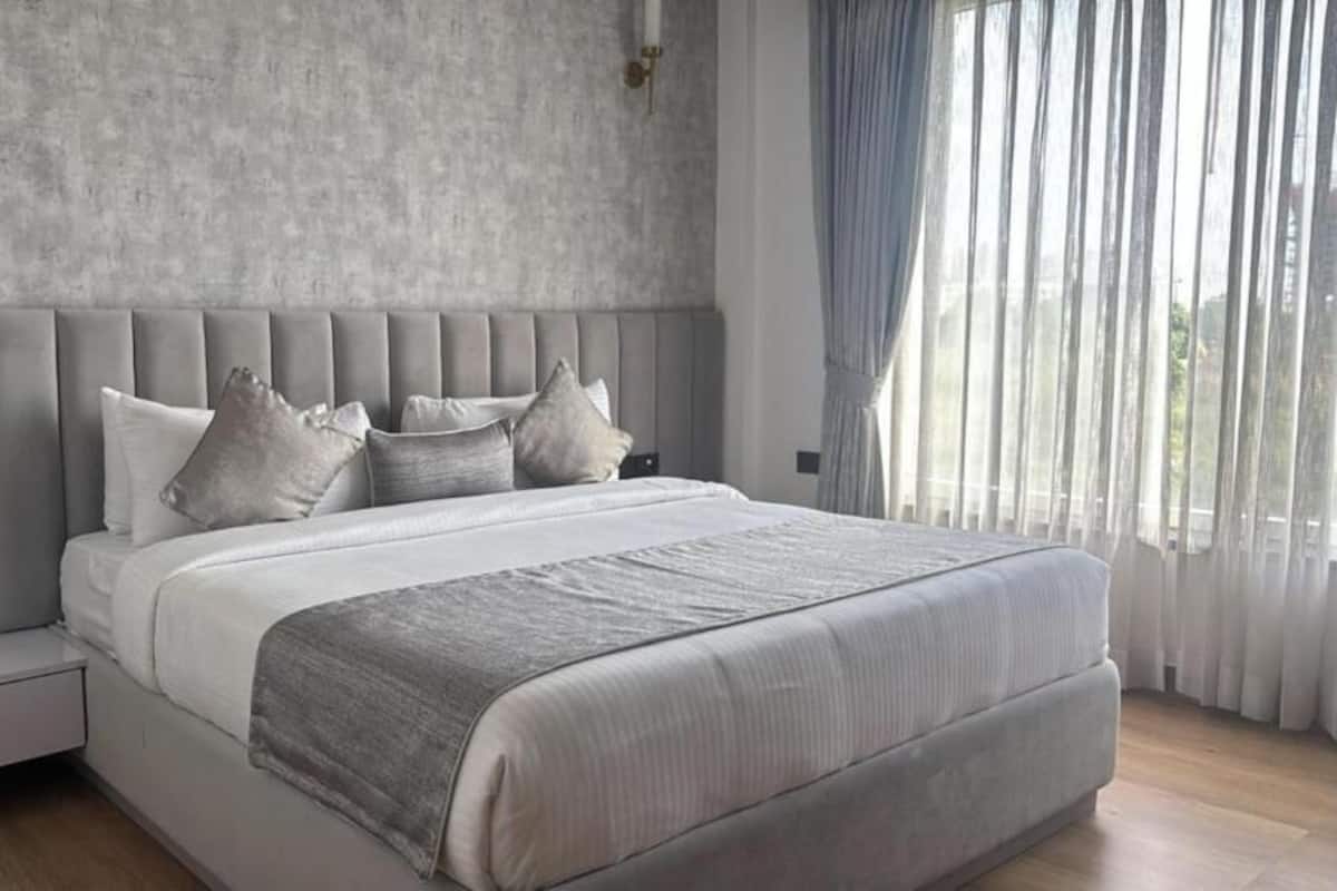 A modern bedroom with a large bed, a nightstand, and a window with curtains.