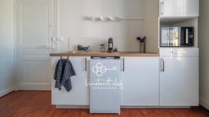 Cozinha moderna com armários brancos, micro-ondas, cafeteira e máquina de lavar louça.