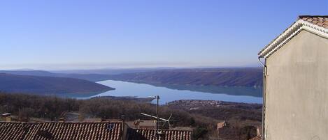 A building with a tiled roof, a view of a lake, and distant hills.