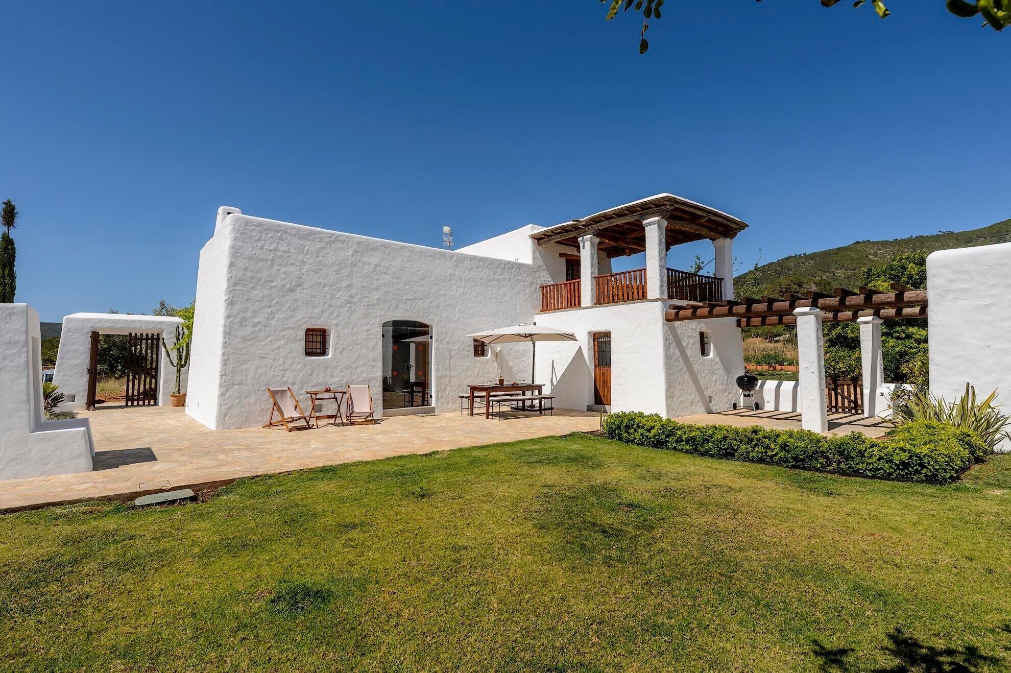 Un bâtiment blanc doté d’un patio, d’une table à manger et de chaises.