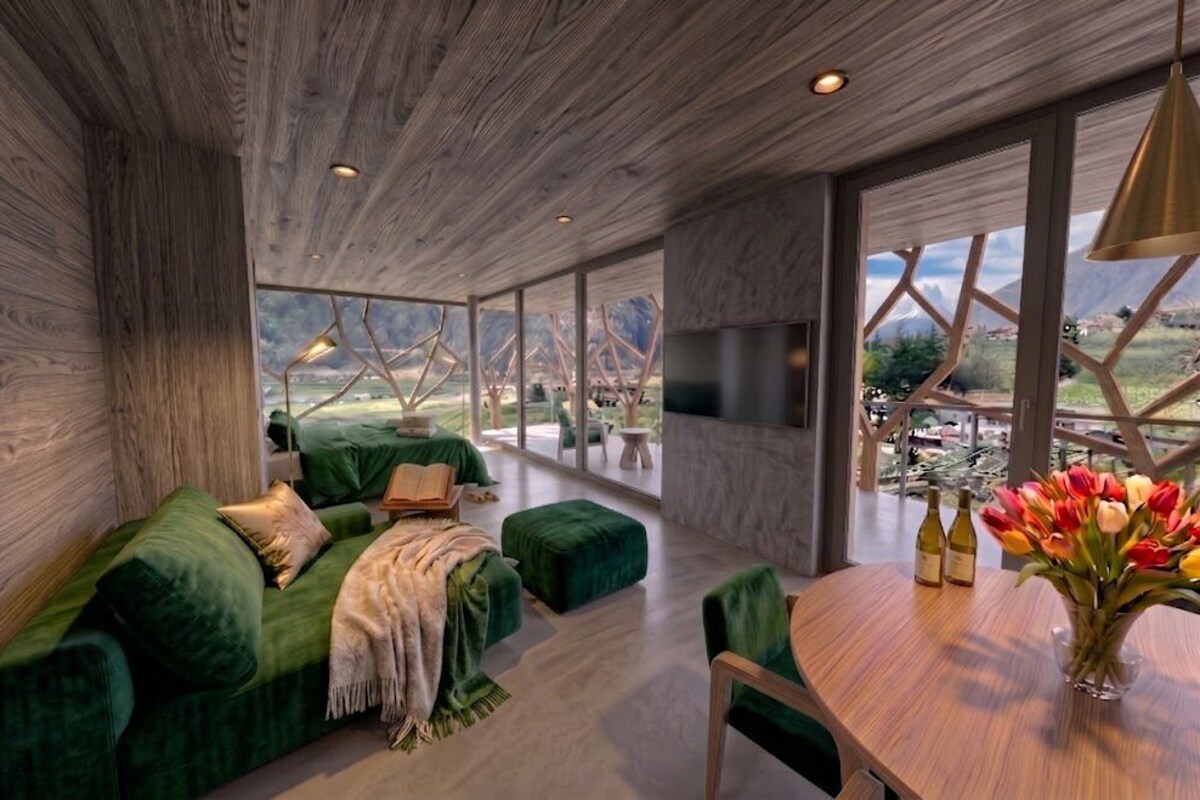 Interior moderno com sofá verde, teto de madeira e uma janela ampla com vista para montanhas.
