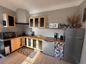 A compact kitchen with wooden cabinets, a microwave, a coffee maker, and a refrigerator. - House just a stone's throw from the sea. 350 meters from the beach. (La Plaine-sur-Mer)