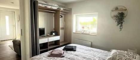 A bedroom with a bed, a wardrobe, a mirror, and a window.