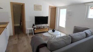 Una sala de estar moderna con un sofá, un televisor y un comedor.