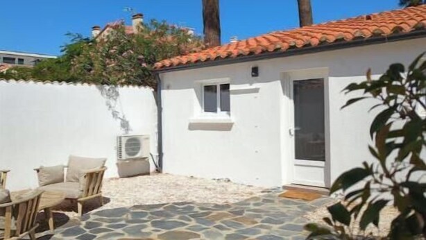 Un edificio blanco con techo de tejas, un patio de piedra y una pared blanca con una ventana.