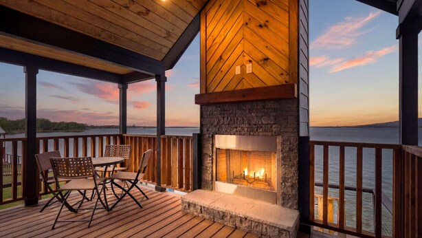 A wooden deck with a stone fireplace and outdoor furniture. - Lakefront Retreat Paradise (Pittsburg)