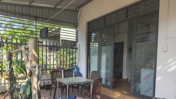 Une terrasse extérieure avec une table et des chaises, un hamac et une porte vitrée donnant sur l’intérieur.