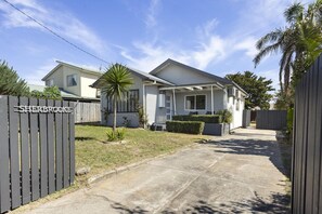 A residential property with a paved driveway, a wooden fence, and a well-maintained lawn. - Sherbrooke, Rosebud. (Rosebud)