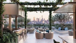 An outdoor seating area with a city skyline view, covered by a pergola with vines, and furnished with sofas and chairs. - Q Hotel Dhaka (Dhaka)